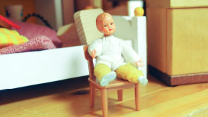 Nahaufnahme: Kinderfigur im Puppenhaus.