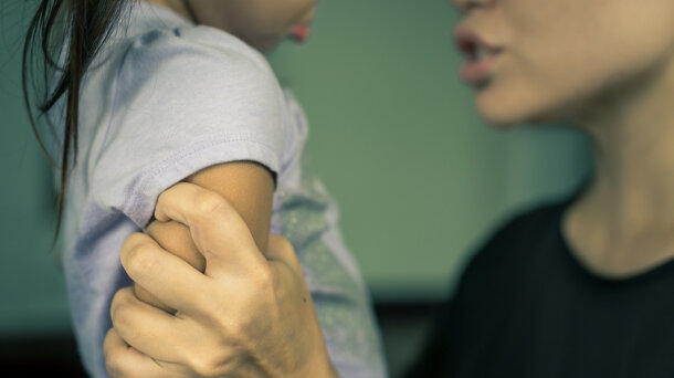 Nahaufnahme: Eine Person greift ein Kind am Arm.